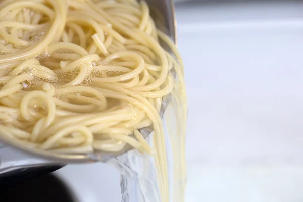 Cooking spaghetti noodles meal: strain the pasta from water — Stock Photo, Image