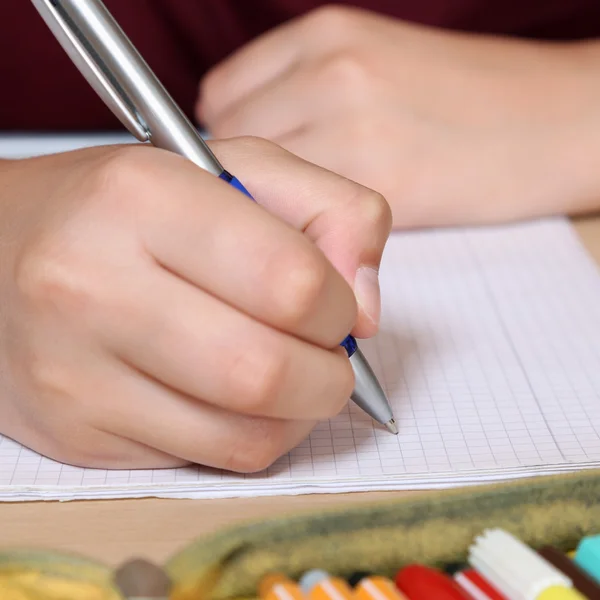 Student skriver med hand i sin skrivbok i skolan — Stockfoto