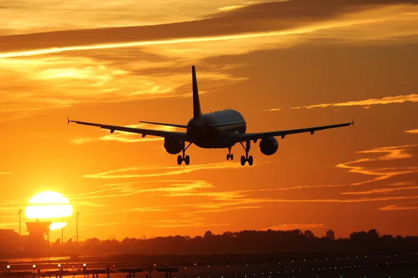 Самолёт приземляется в аэропорту на закате — стоковое фото