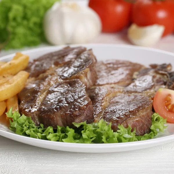 Costeletas de porco bifes de carne com batatas fritas e salada no prato — Fotografia de Stock