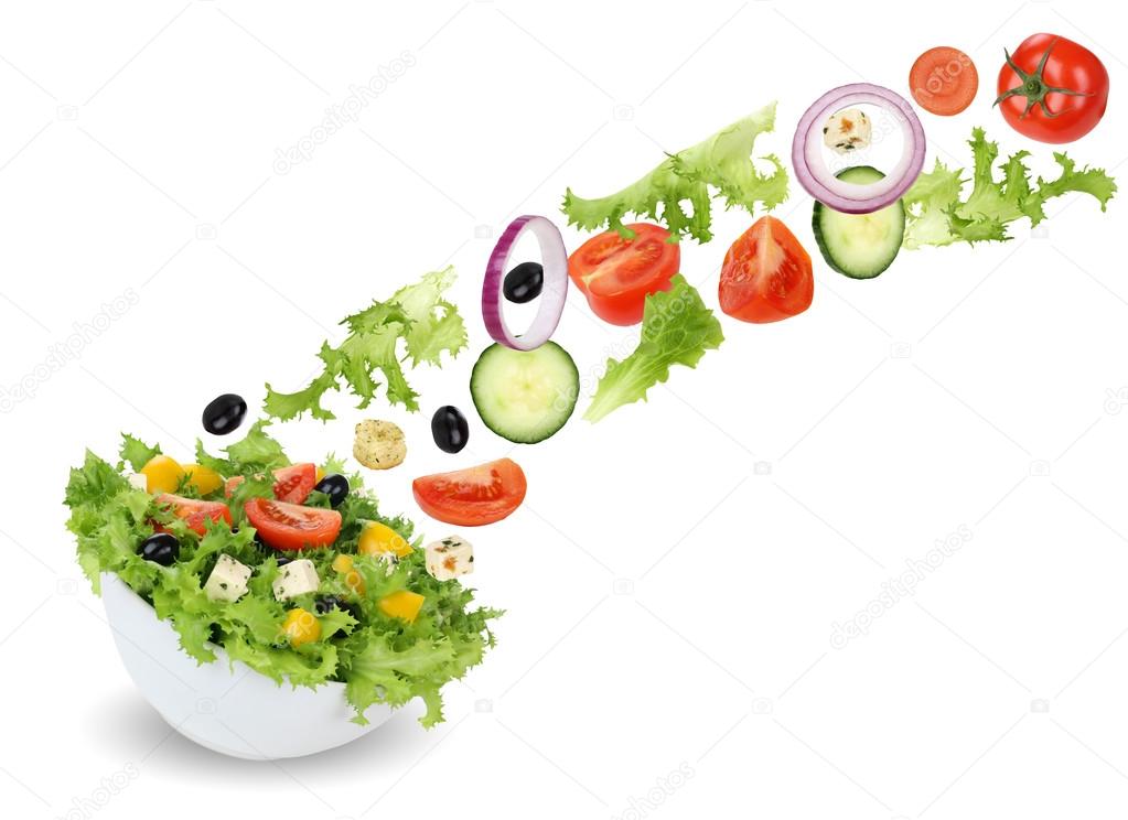 Flying green salad in bowl with tomatoes, onion, olives and cucu