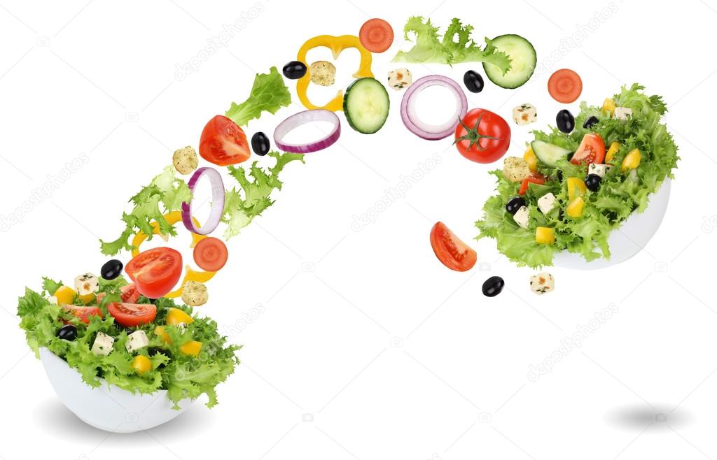 Flying salad ingredients in bowl with tomatoes, lettuce, onion a