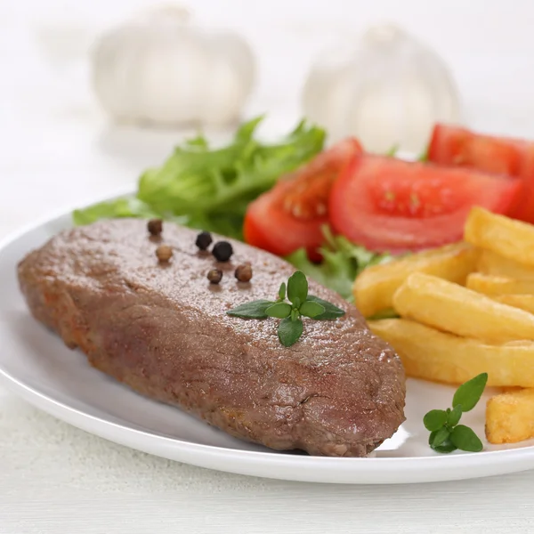 Fried beef steak meat meal with fries, vegetables and lettuce on — Stock Photo, Image