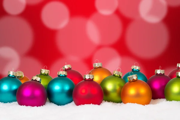 Πολλές πολύχρωμες μπάλες Χριστούγεννα διακόσμηση με χιόνι στο παρασκήνιο — Φωτογραφία Αρχείου