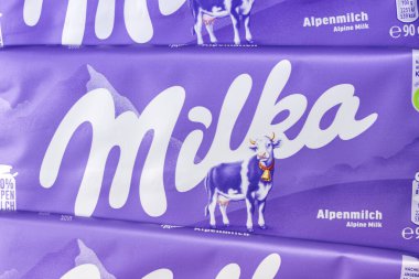 Stuttgart, Almanya - 18 Eylül 2025: Milka çikolatalı 90g bar Alp sütü yakın plan şirket logosu Stuttgart, Almanya.