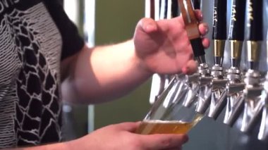 Barmen bardaki bardağa taze bira dolduruyor.,