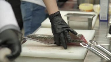 Eldivenli biri masada bıçakla balık keser.