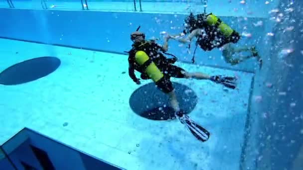 Mergulhadores nadam em uma piscina azul profunda de treinamento de água — Vídeo de Stock