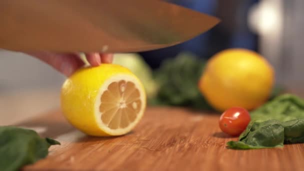 Női kéz vágás friss citrom fa vágódeszka segítségével konyhakéssel. Szeletelt citrom. — Stock videók
