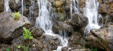 Parlak küçük şelale taşların üzerinden akıyor.