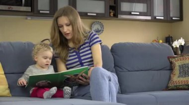 Koltukta oturan kızına şirin kitapta görüntüleri gösteren dikkatli anne