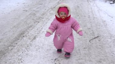 Küçük bebek kız kış park karlı yolda yürümek.