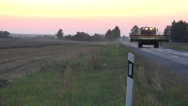 Pesante combinare macchina mietitrice guida su strada modo dal lavoro nei campi al tramonto della sera. 4K — Video Stock