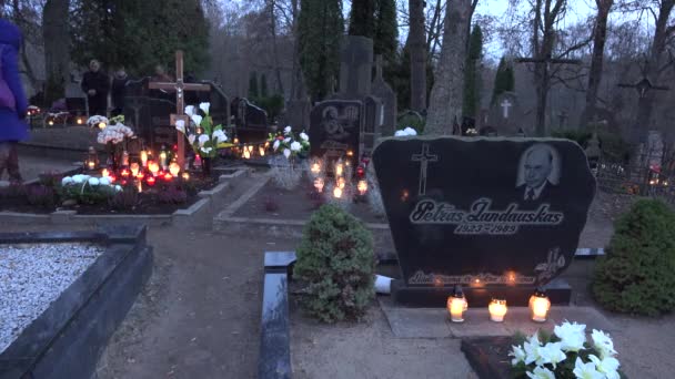 Makam dengan lilin yang menyala dan orang-orang mengunjungi pemakaman pada hari libur agama. 4K — Stok Video