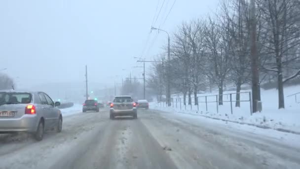 Automobiles cars driving on roadway in snow storm in the city. 4K — Stock Video