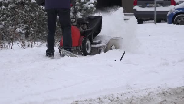 Worker man with snow blower machine clean sidewalk on street side in winter. 4K — Stock Video