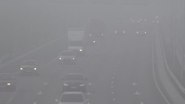 Intenso tráfego de automóveis na estrada envolto em névoa espessa. 4K — Vídeo de Stock