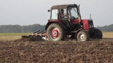 Çiftlik işçisi traktör pulluk ile sonbahar sezonunda alan toprak açmak. İzleyin. 4k