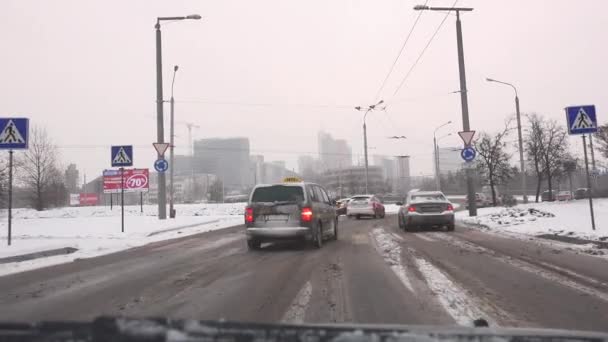 Tormenta de nieve cae en la calle de la ciudad y coches en horas punta. 4K — Vídeos de Stock