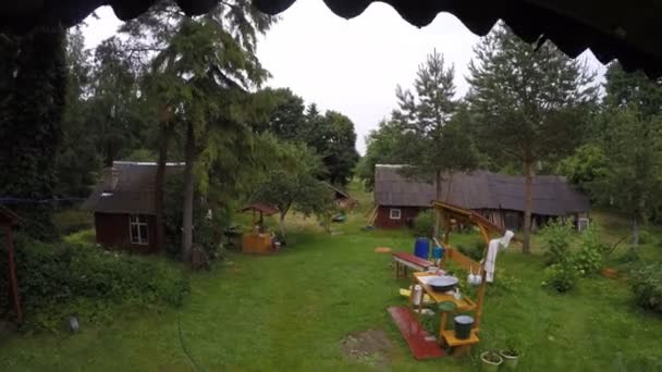 Casas de pueblo de madera y gotas de lluvia caen de la azotea. 4K — Vídeo de stock