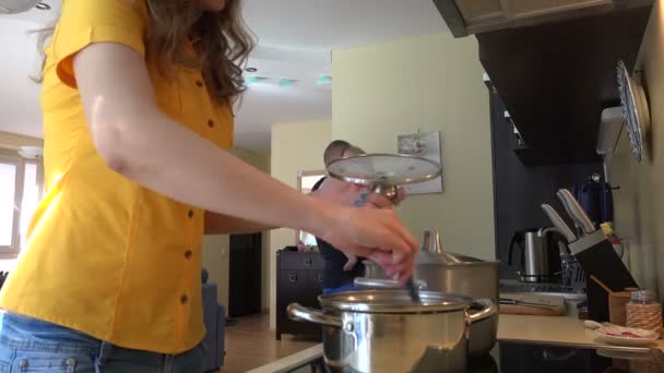 Homem com bebê em mãos e mulher misturando alimentos em panela de vapor. 4K — Vídeo de Stock
