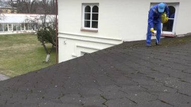 Temizlikçi adam sprey moss evin çatısında büyüyen kimyasallar ile