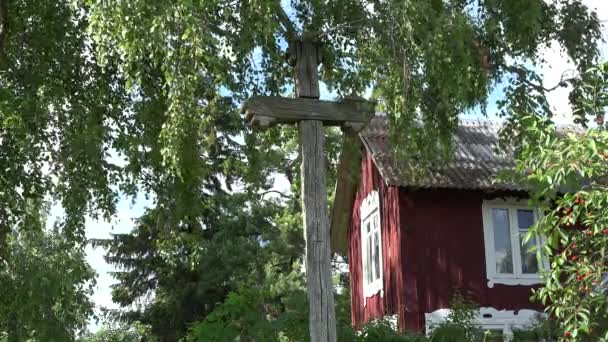 Cruz de madera retro entre ramas de abedul en movimiento cerca de la casa rural. 4K — Vídeos de Stock