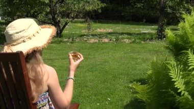 Kadın kız içki bira viski Park ahşap sandalye oturamaz. 4k