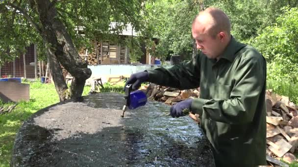 Jonge man met gasbrander en hete teer repareren zijn bodem boot in de tuin. 4k — Stockvideo
