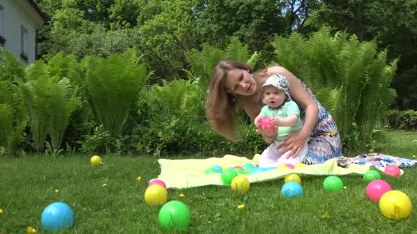 Mutter mit kleinem Baby spielt mit buntem Ball im grünen Park. 4k — Stockvideo