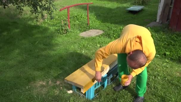 Amateur worker boy painting wood surface with brush in yellow color. Closeup. 4K — Stock Video