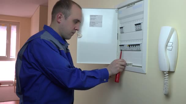 Man in blauwe uniform werken op een circuit breaker in platte house — Stockvideo