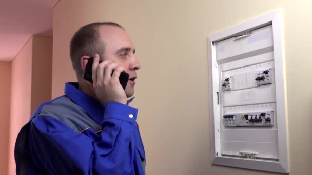 Mann arbeitet an einem Schutzschalter und telefoniert — Stockvideo