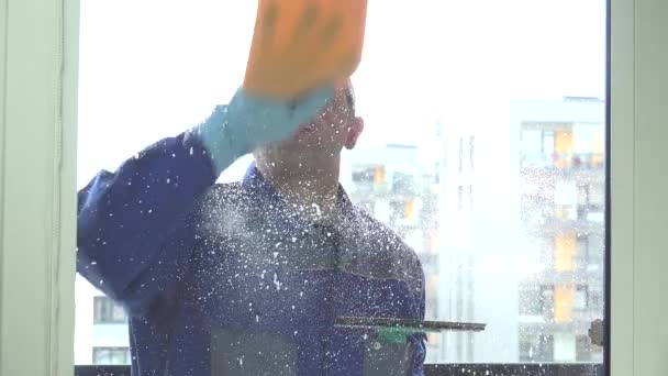 Male window washer spray and wipe window with wiper tool. — Stock Video