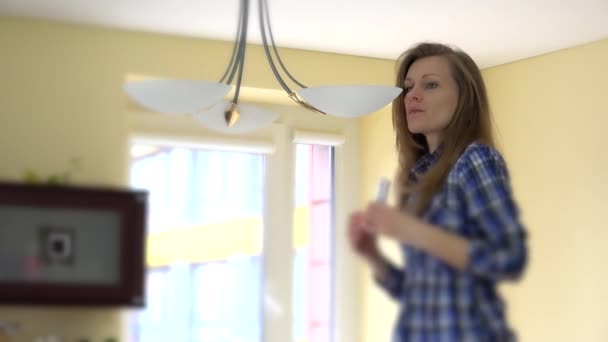 Woman screw eco light bulbs in chandelier. — Stockvideo