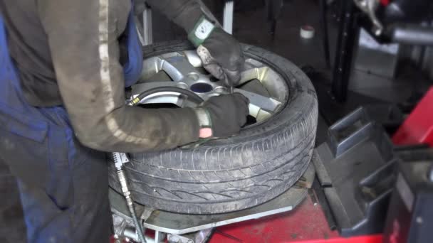 As mãos sujas do trabalhador inflam o compressor sagacidade do ar do pneu na máquina de montagem . — Vídeo de Stock