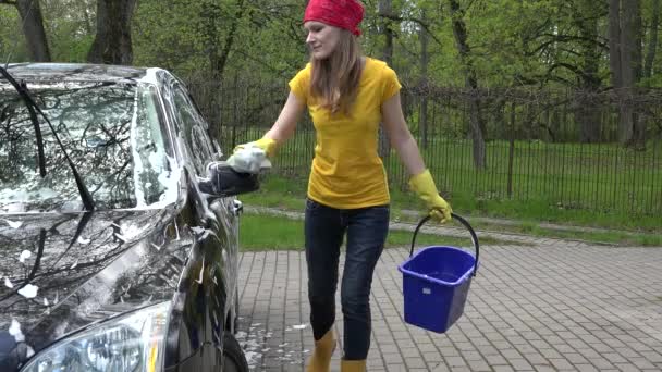 Jolie femme lave sa voiture avec une éponge en plein air . — Video