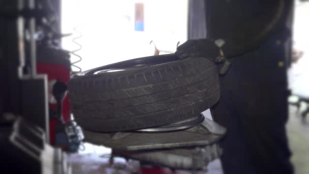 Механик в грязной работе надевает шину на колёса . — стоковое видео