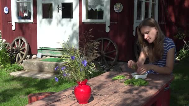 Fille coquille pois à table en bois dans le pays avec la vieille maison. 4K — Video