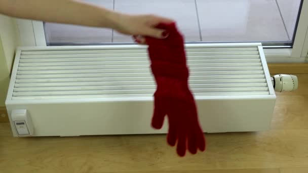 Meisje hand zetten rode wollen handschoenen op radiator thuis. — Stockvideo