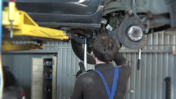 Monteur reparatie van een auto in zijn garage en diverse hulpmiddelen op doos. Kantelen naar beneden. — Stockvideo