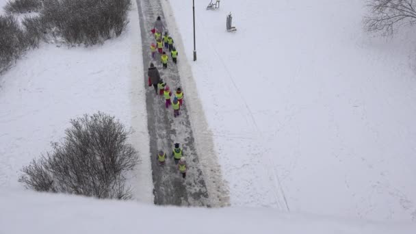 Τα μικρά παιδιά με παραμάνα έχουν βόλτα στο πάρκο χειμώνα καλύπτονται με πυκνό χιόνι. 4k — Αρχείο Βίντεο