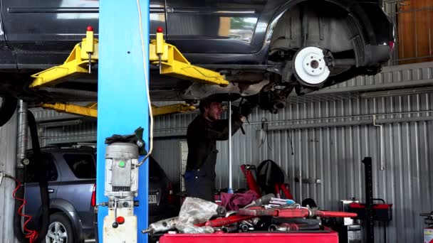 Reparador reparación del sistema de escape en el coche sedán levantado en el taller de reparación de automóviles — Vídeos de Stock