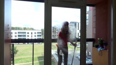young pretty woman spray chemical and wipe window at clients home.