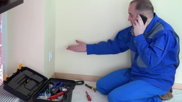 Elektriker Mann telefoniert mit Handy und steckt Sicherheitsnadel an Steckdose. — Stockvideo