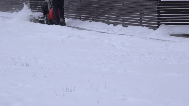 El hombre que trabaja con la máquina de soplado de nieve en el pavimento después de la caída de nieve en invierno. 4K — Vídeo de stock