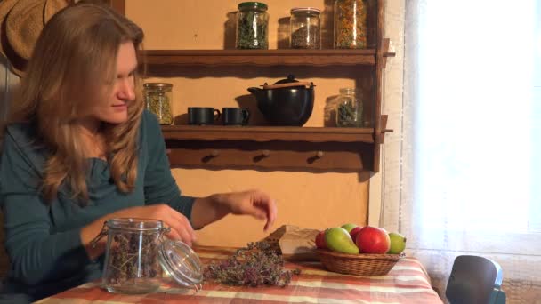 Mujer herbolaria poner hierbas de mejorana seca en el estante de madera. 4K — Vídeo de stock