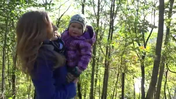 Mulher feliz com bebê menina nos braços andar no parque outonal. 4K — Vídeo de Stock