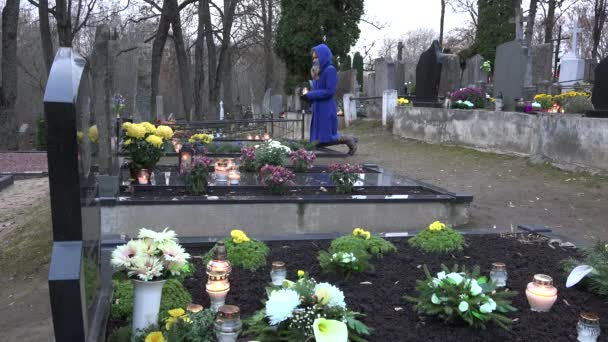 女人在膝盖上的把蜡烛放在墓的家庭成员和祈祷。4 k — 图库视频影像