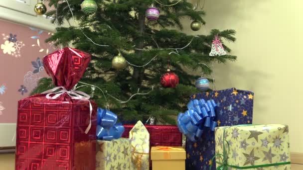 Kleurrijke aanwezig geschenkverpakkingen met lint onder kerstboom — Stockvideo